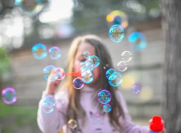 Preschooler blowing bubbles in a park 