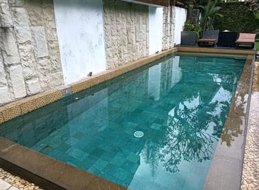 Desain kolam renang minimalis modern dengan air jernih di halaman belakang rumah