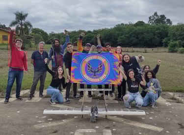 Membros da equipe segurando a bandeira e com mãos erguidas, atrás do avião de 2023