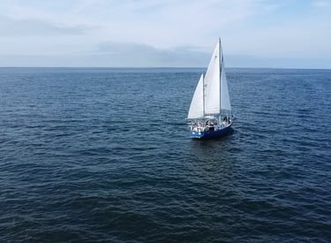 Sailing vessel Our Passion with three sails up heading towards the horizon