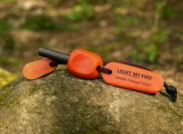 Light My Fire Swedish FireSteel with orange handle on mossy rock for emergency fire