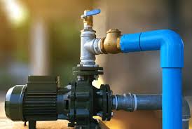 Electric water pump motor connected to blue PVC piping and brass valves for industrial irrigation.