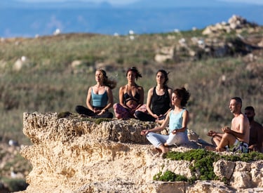 a group of people sitting in meditation on a cliff