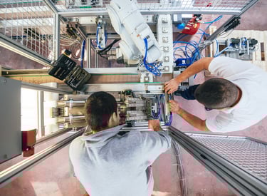 two men working on a robotic machine that is being worked on and upgraded