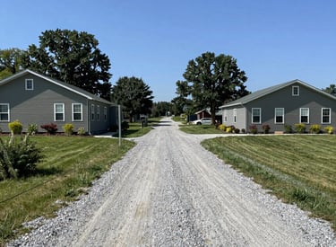 Freshly laid gravel driveway stretching toward a cozy home entrance.