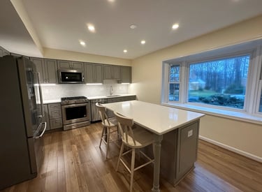 A beautifully updated kitchen featuring gray shaker cabinets, quartz countertops, and warm LVP