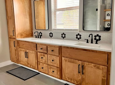 Modern master bathroom with double wood vanity, white quartz counters, and black hexagon tile accents.