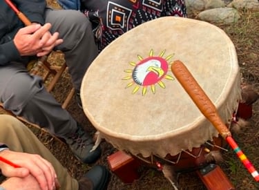 Personnes autour d'un gros tambour traditionnel au sol. 