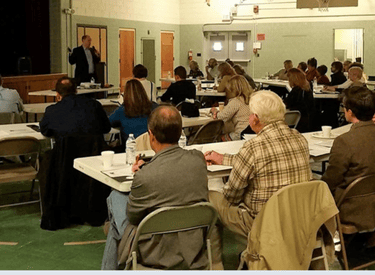 a group of people sitting at tables in a room during workshop
