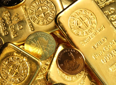 A collection of shiny 1 kilogram Argor-Heraeus gold bars and gold bullion coins for investment.