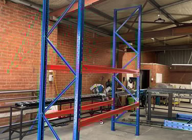 Heavy-duty steel pallet racking with assembled uprights and two solid shelves.