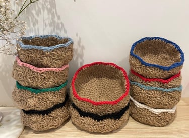 Stacks of handmade small jute crochet baskets with colorful yarn rims for home storage and organization.