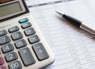 Close-up of a financial ledger and calculator on a wooden desk, symbolizing expense management.