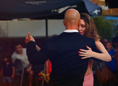 Una pareja bailando tango argentino al aire libre por la noche.