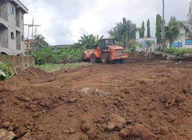 Orange wheel loader excavator clearing soil at a residential construction site for land preparation.