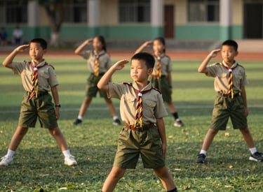 A vibrant photograph of Southeast Asian children in scout uniforms practicing outdoor activities in a green school yard, warm golden hour lighting, professional composition.