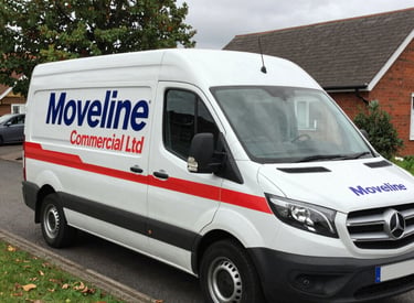 Professional movers loading boxes into a long-wheelbase van in a UK neighborhood