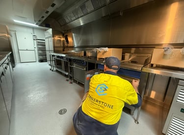 Professional plumber installing commercial kitchen equipment and gas appliances in a restaurant.