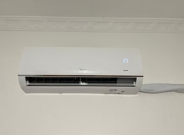 White Midea inverter split air conditioner unit mounted on a wall showing a digital temperature display.