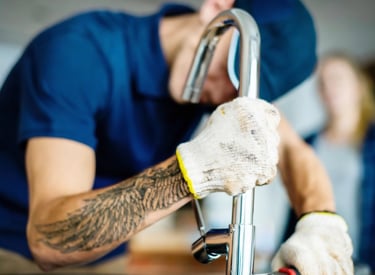 Professional plumber installing new kitchen faucet with modern chrome tap