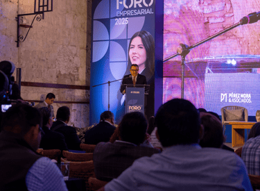 Speaker at Foro Empresarial 2025 business conference podium addressing a seated audience in an auditorium.