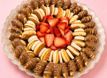 Un plato de mini panqueques con fresas frescas, rodajas de plátano y nutella.