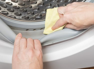 une personne nettoie avec un chiffon le joint de la machine