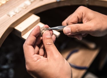 Joyero utilizando pinzas de punta fina para elaborar joyería artesanal de filigrana en oro.