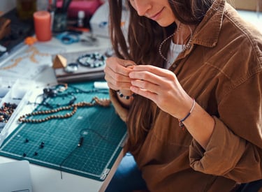 mujer sonriendo mientras elabora una pieza de joyería artesanal 