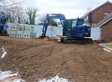 Blue JMC mini excavator loading dirt into a 3 tonne dumper on a residential garden construction site.
