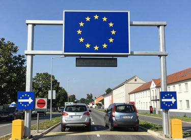 Customs officer reviewing official documents at a European border checkpoint under clear skies.