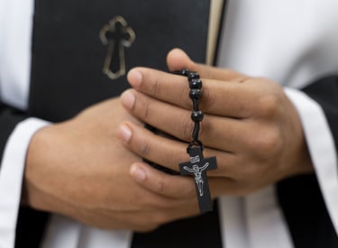 padre com rosário durante cerimónia fúnebre
