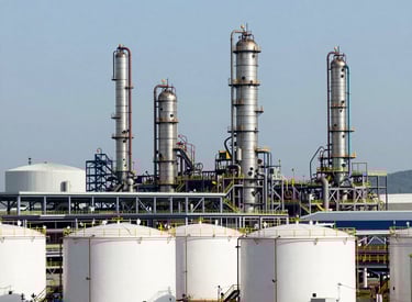 Oil rigs silhouetted against a vibrant sunset over the ocean.