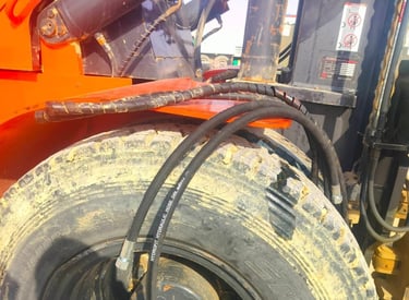 Close-up of a heavy machinery tire with new black hydraulic hoses installed on industrial equipment.