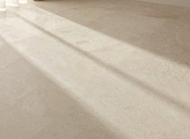 Warm beige travertine tiles laid in a herringbone pattern with golden veining details.