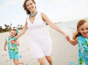 mother with children holding hands at beach