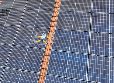 A thermal imaging drone performing an aerial inspection of residential rooftop solar panels.