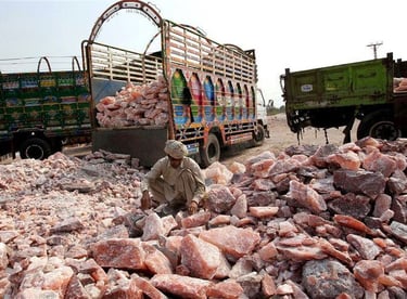 A worker sorts raw Himalayan pink salt rocks near transport trucks at a salt mining site in Pakistan