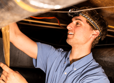 Jayden Kelly doing maintenance work in a crawlspace