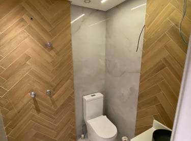 Banheiro reformado pela Nattú Engenharia com porcelanato claro e madeira em estilo espinha de peixe