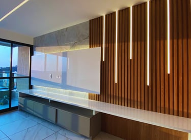 Sala reformada pela Nattú Engenharia com painel de madeira iluminado e piso de porcelanato claro