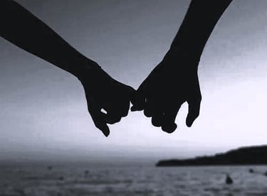 A couple holding hands in front of sea. The picture signifies it is time for pleasure on vacation