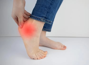 Woman holding her heel in pain highlighting heel pain and plantar fasciitis symptoms
