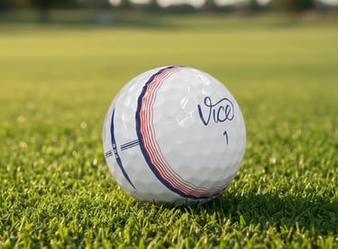 A white Vice Pro golf ball with red and blue alignment lines resting on a lush green grass fairway.