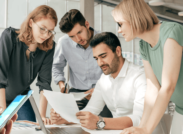 a group of people standing around a laptop computer