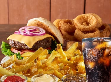 a burger with fries onion rings and a soft drink