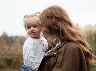 Mother holding her daughter in her arms and smiling at her