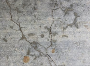 Top down view of weathered grey concrete floor with visible cracks and stains.