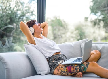 a woman sitting on a couch with her laptop. She is practicing English with music