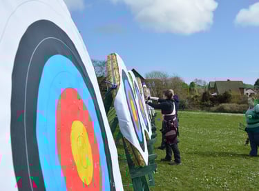 a man and woman are standing in front of an archery target